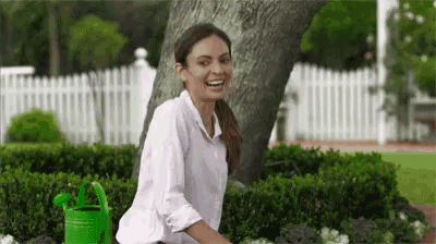 a woman is sitting next to a green watering can