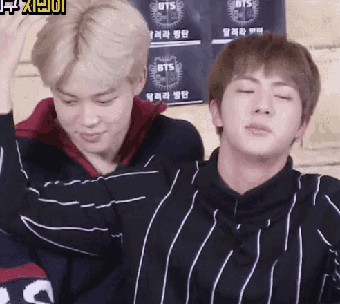 a couple of boys standing next to each other with a poster that says bts on it
