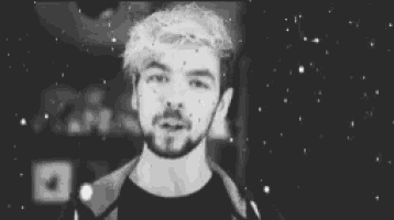 a black and white photo of a young man with a beard and blonde hair .