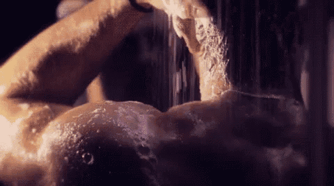 a man is taking a shower and washing his face with soap and water .