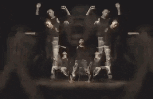 a man with his hands on his face is surrounded by a group of men dancing .
