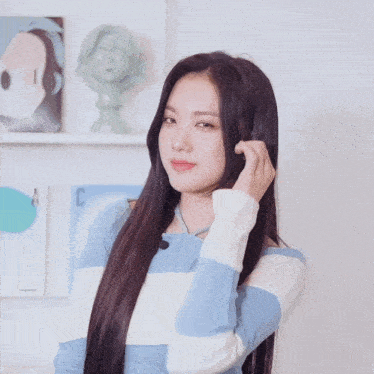 a woman with long black hair wearing a blue and white striped sweater