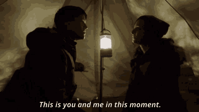 a man and a woman in a tent with the words this is you and me in this moment below them