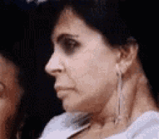 a close up of a woman 's face with earrings and a serious look on her face .