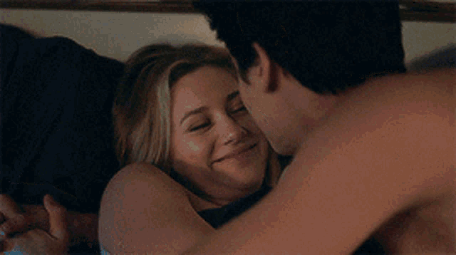 a man and a woman are laying on a bed and the woman is smiling