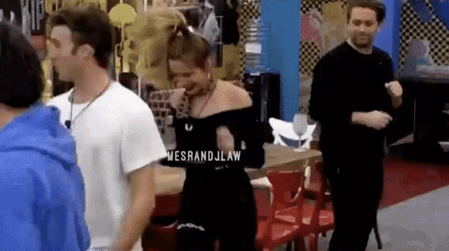 a woman in a black dress is dancing in a room with a group of people .