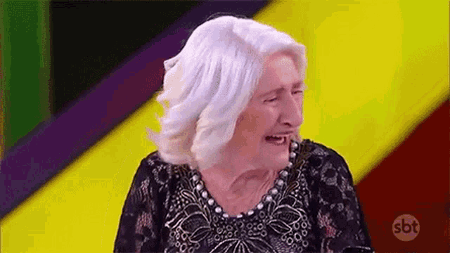 an elderly woman with white hair is laughing while wearing a black dress .