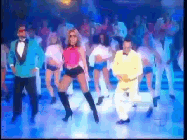 a group of people are dancing on a stage in a club