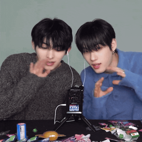 two young men are sitting at a table with candy and a microphone that says sony on it
