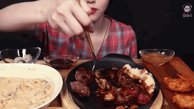 a woman in a plaid shirt is eating a steak with a fork