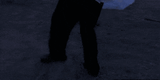 a person standing in a field with a car in the background and a tree in the foreground
