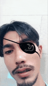 a man with a beard is wearing a black eye patch