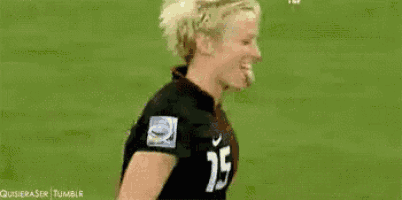 a female soccer player wearing a black jersey with the number 15 on it is blowing bubbles .