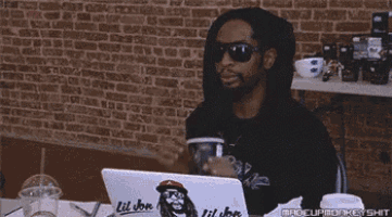 a woman is sitting at a table with a laptop and drinking through a straw .