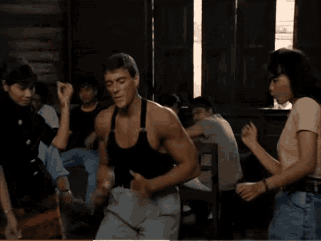 a man in a black tank top is dancing in a room