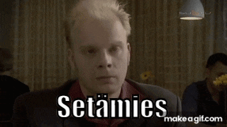a man in a suit is sitting at a table with the words " setamies " on the screen behind him