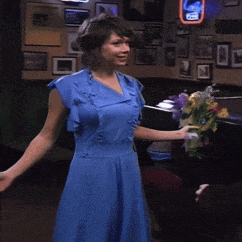 a woman in a blue dress is holding a bouquet of flowers in a bar