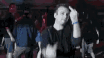 a man is giving the middle finger in front of a crowd at a concert .
