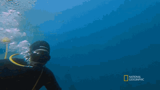 a man is swimming in the ocean with the words national geographic behind him