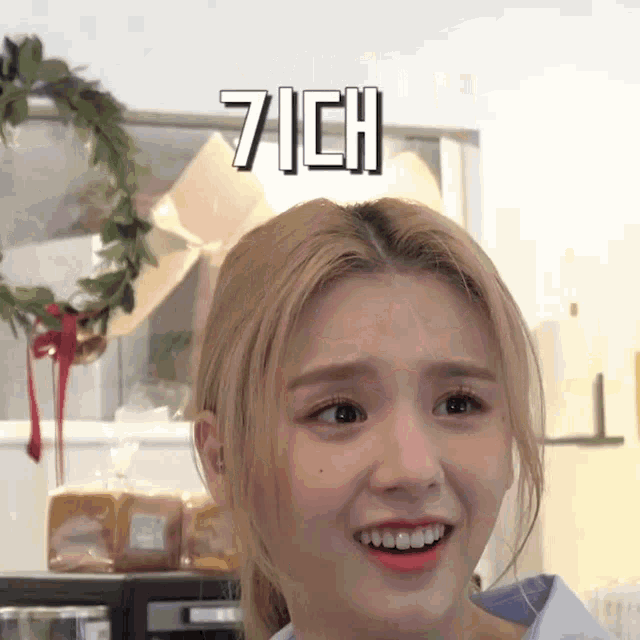 a woman with blonde hair is making a funny face in front of a microwave and a wreath .
