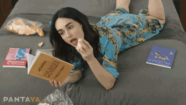 a woman is laying on a bed reading a book titled mujeres