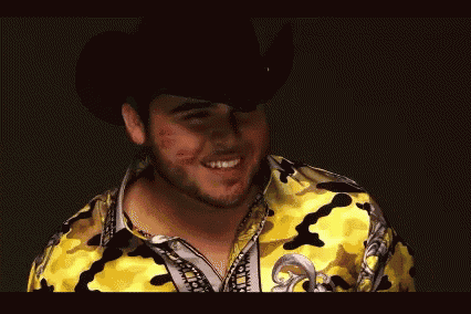 a man wearing a cowboy hat and a yellow shirt with a rhinestone on it