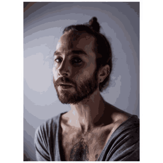 a man with a beard and a bun looks at the camera