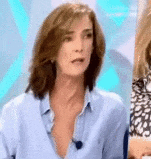 a woman in a blue shirt with a microphone on her neck is making a funny face