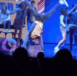 a group of people are dancing on a stage in front of a sign that says dr