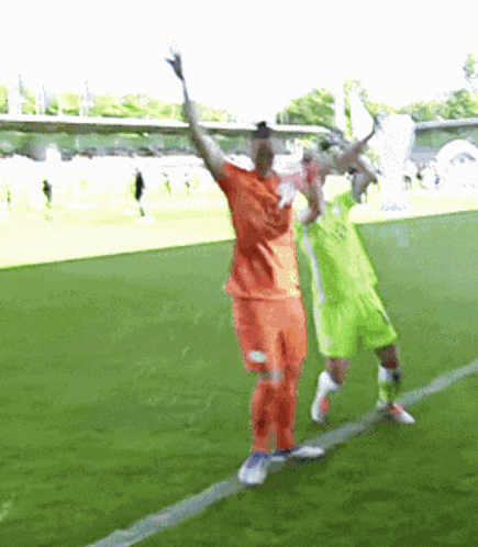 two soccer players are holding up their arms in the air