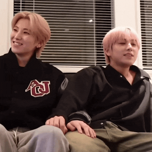 two men are sitting next to each other on a couch holding hands .