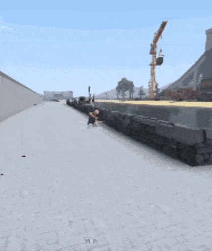 a brick walkway with a crane in the background and a person laying on the ground