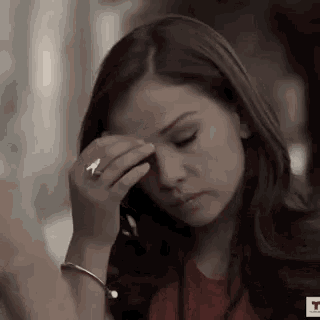a woman with a ring on her finger wipes her forehead with her hand