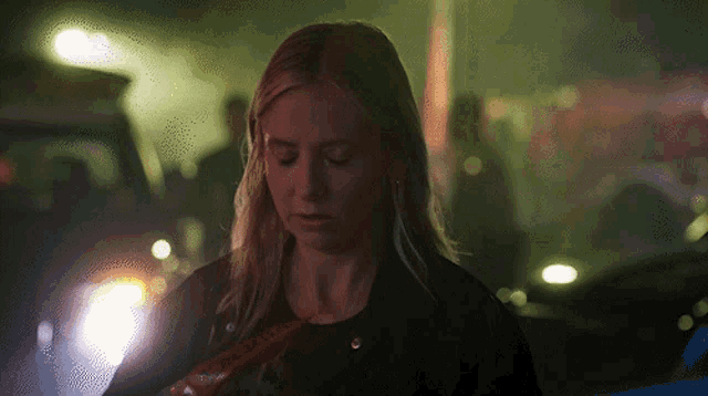 a woman standing in a dark room with a red ribbon that says ' ambulance ' on it
