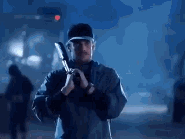 a man in a baseball cap is holding a knife .