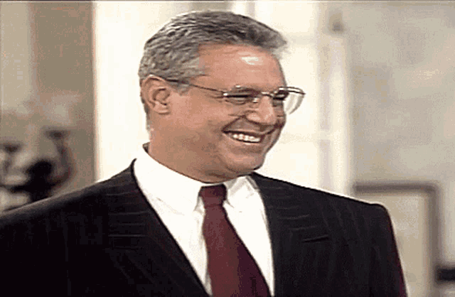 a man in a suit and tie is smiling and laughing
