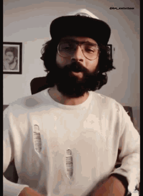 a man with a beard and glasses is wearing a hat and a white shirt