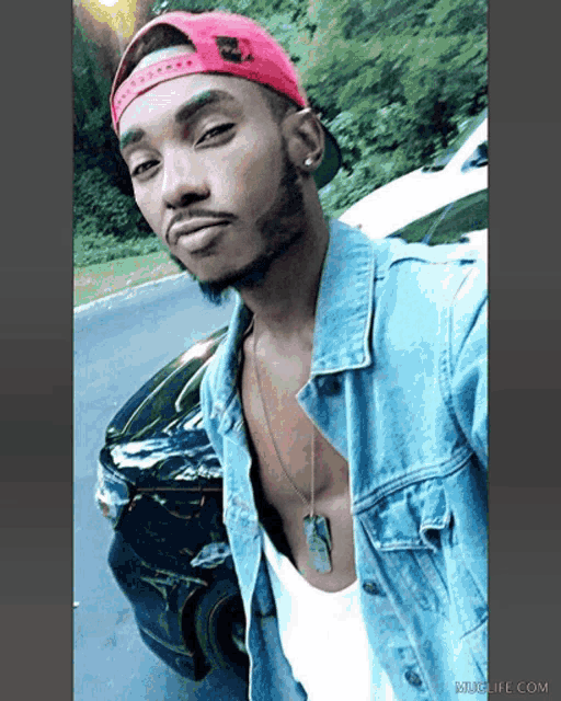 a man wearing a red nike hat and a blue denim jacket takes a selfie
