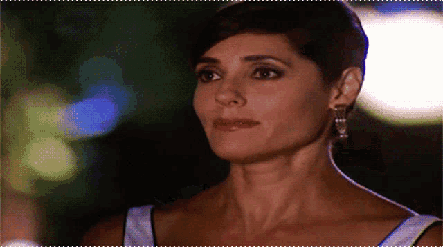 a woman with short hair is wearing earrings and a white top