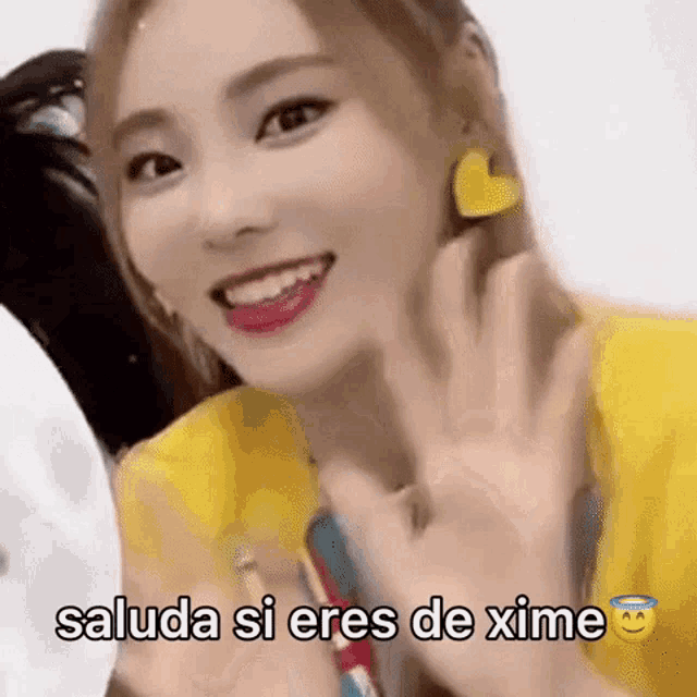 a close up of a woman wearing a yellow shirt and yellow earrings .