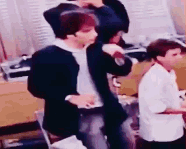 a group of people are standing in a room and dancing .
