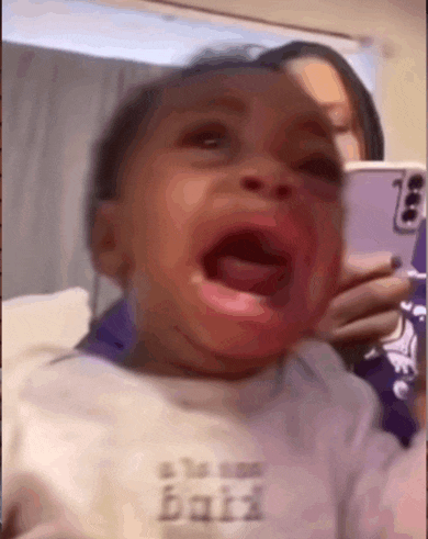 a baby is crying and a woman is holding a cell phone .