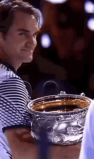 a man in a striped shirt is holding a silver trophy
