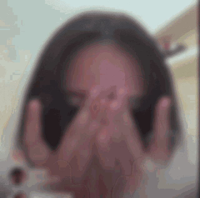 a woman covering her face with her hands in a blurry photo