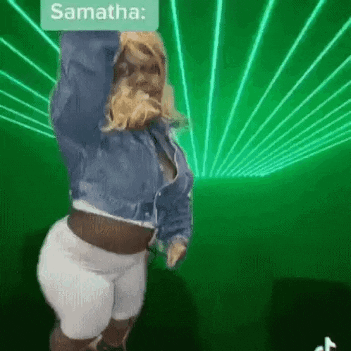 a woman in a denim jacket is dancing in front of a green laser light .