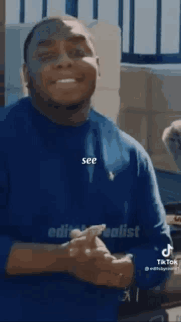 a man in a blue shirt is making a funny face while talking to someone .