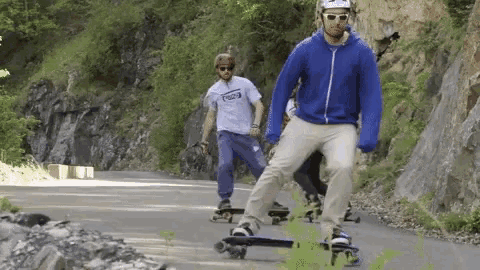a man wearing a helmet and sunglasses rides a skateboard down a road