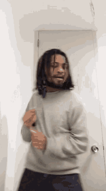 a man with long hair and a beard is dancing in a room .