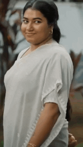 a woman in a white dress is smiling for the camera .