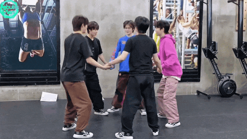 a group of young men are holding hands in a gym with a rowing machine in the background